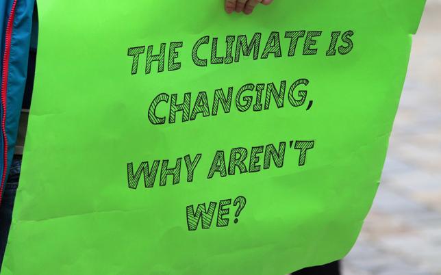 Photo for blog post, a green sign with words The Climte is Changing, Why aren't We